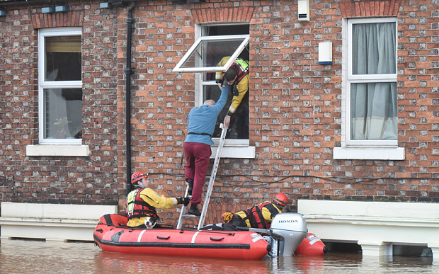 A man is helped from a first floor window by rescue teams in Carlisle, Cumbria, UK (Dec, 2015). Photo: Paul Kingston/North News